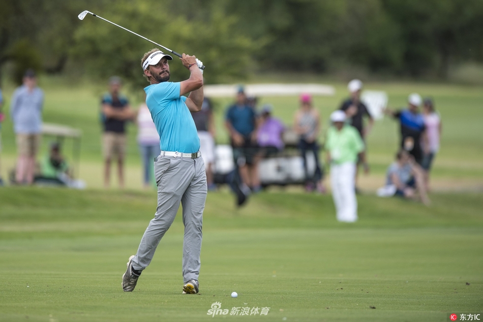 观众聚集在果岭后方山坡上，聚精会神观看比赛，远处是太阳城独特的度假村建筑