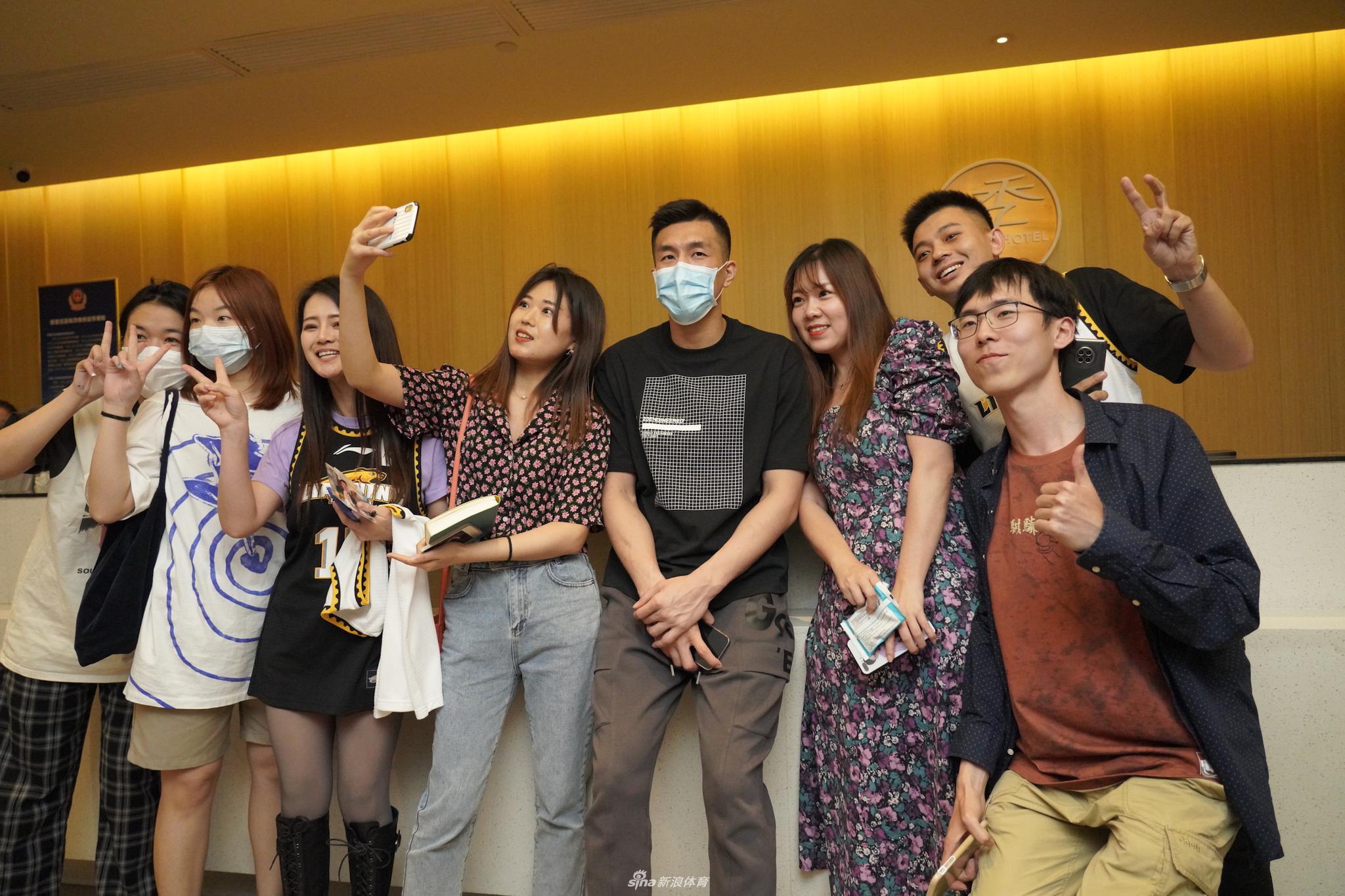 面对镜头的郭艾伦露出搞怪表情，他身后是几位笑得合不拢嘴的女粉丝，展现了球星与球迷之间融洽的互动。