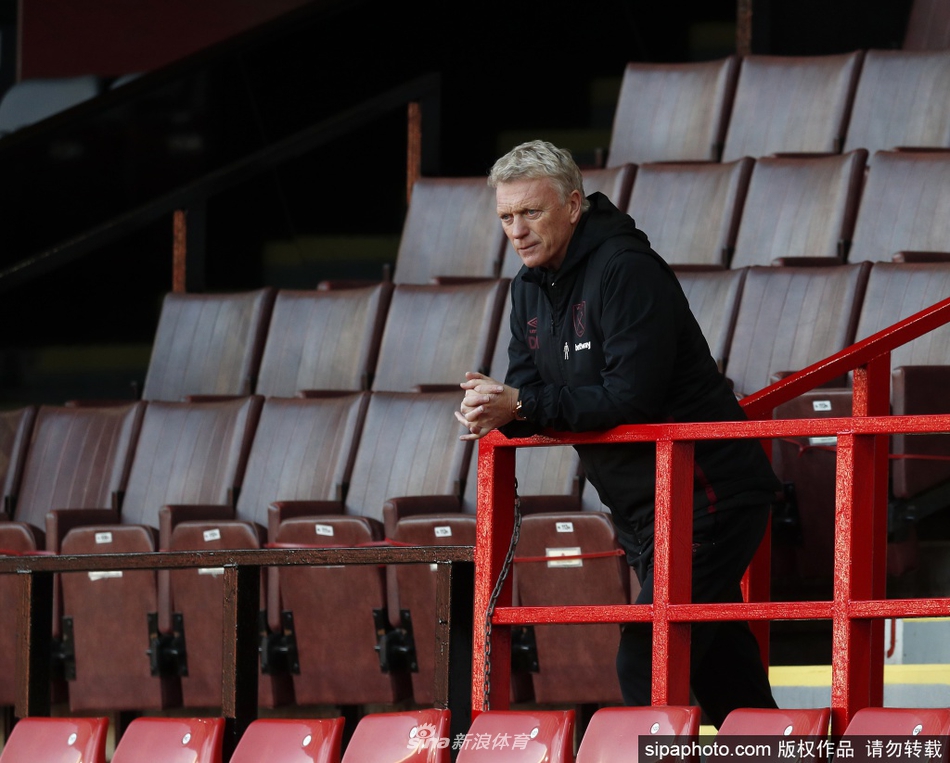 莫耶斯手捧奖杯展露儒雅笑容，身后背景的颁奖礼灯光映照出他带领西汉姆联走向复兴的坚定与荣耀时刻