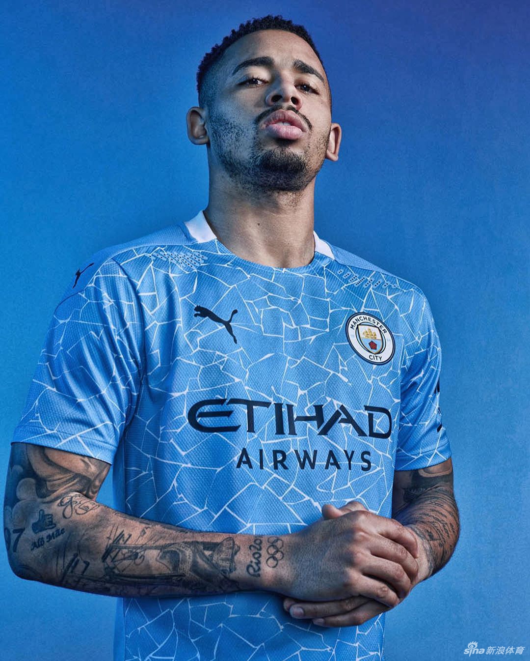 曼城球衣细节特写，可以看到胸前暗纹的精美轮廓，金色的队徽与赞助商标识在阳光下熠熠生辉，诉说着球队的雄心壮志