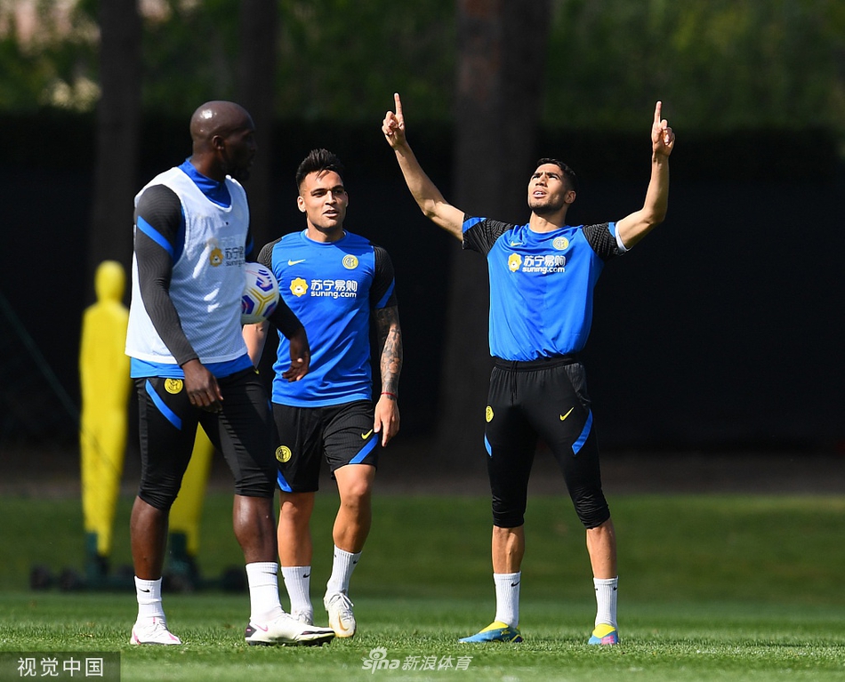 夺冠功臣卢卡库在训练场上开心地摆弄着足球，他身后的队友们正围在一起分享香槟，背景是苏宁训练中心的蓝天绿地。