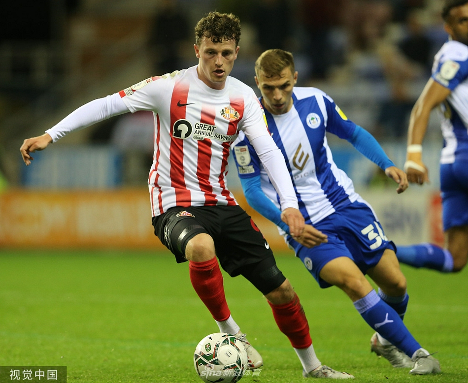  桑德兰前锋布罗德黑德破门瞬间，他高高跃起挥舞手臂庆祝，身后的维冈竞技后卫面露无奈，看台上客队球迷区一片欢腾。