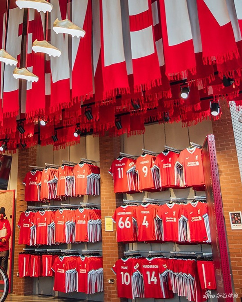 展示架上，全新的客场球衣以其独特的渐变图案引人注目，设计灵感源自利物浦城市的象征利弗鸟与香克利大门的茛苕叶纹路，与一旁的主场战袍交相辉映，共同构成了新赛季完整的视觉图腾。