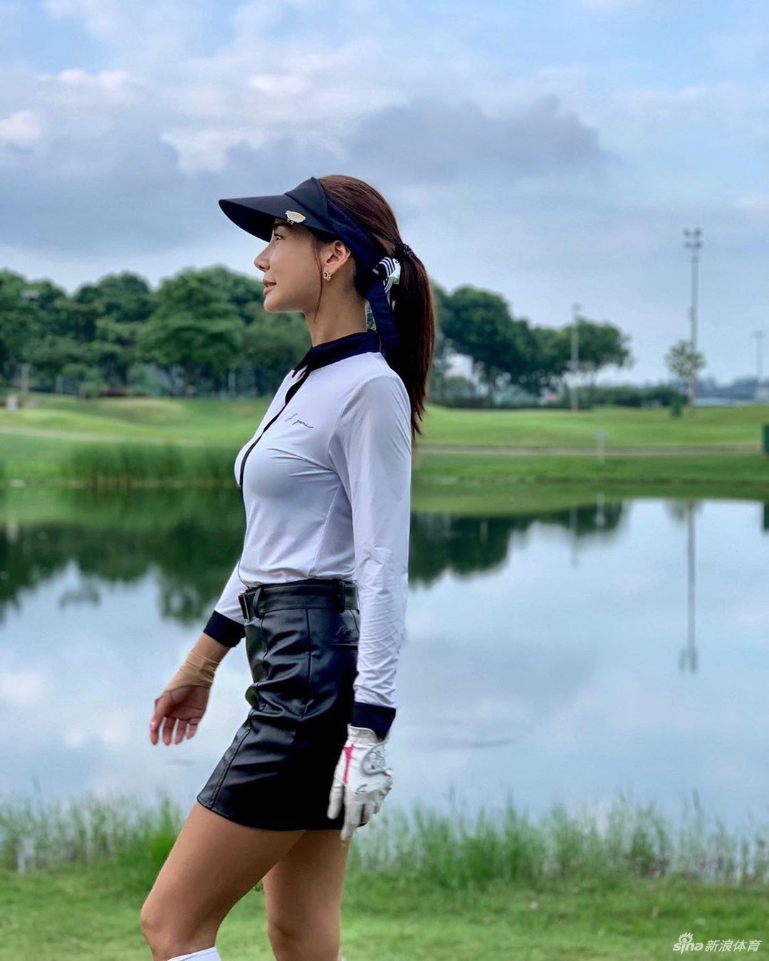 漫步于开阔球道，手提球杆的背影从容自在，与广阔绿茵融为一体