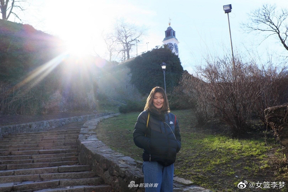 训练场上李梦双手抱球，神情认真投入，背景里模糊的场馆光影衬托出她专注的瞬间。