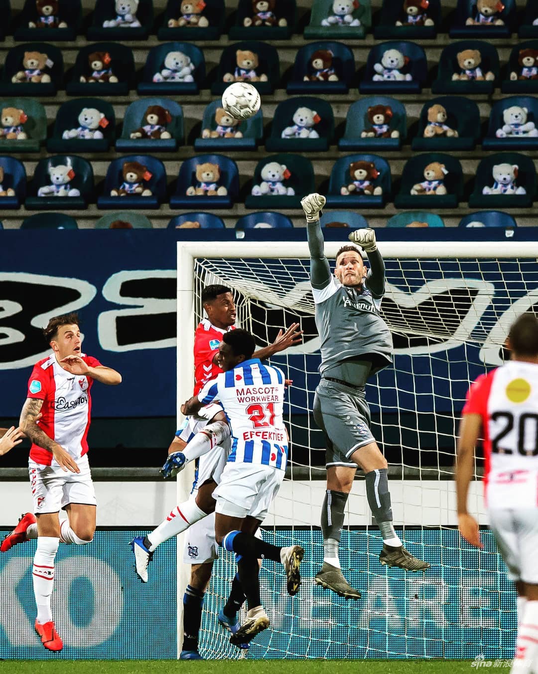 一只身穿海伦芬主场橙色球衣的泰迪熊，孤独又坚定地坐在空旷的看台座椅上，胸前仿佛闪烁着为患癌儿童加油的光芒。