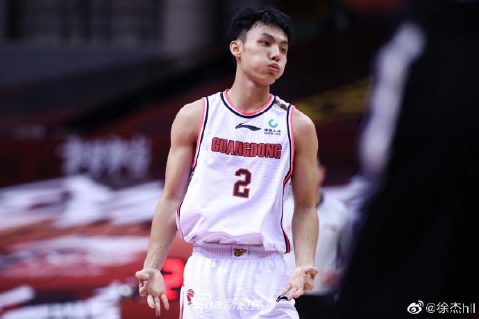 徐杰手持篮球摆出运动姿态,身穿潮流运动混搭服装,在摄影棚光影交错下,将体育的力量感与时尚的线条感完美融合