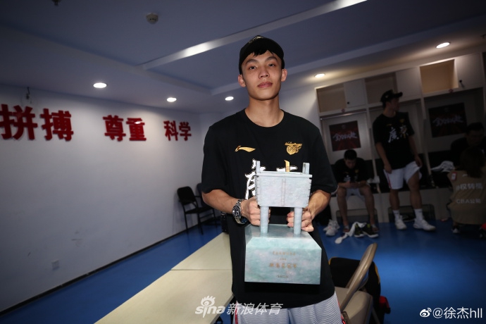 徐杰在GQ时尚拍摄现场的花絮瞬间,脸上带着轻松的笑容,背景是专业的摄影器材,画面构图充满故事感,展现了他赛场之外亲和力十足的一面