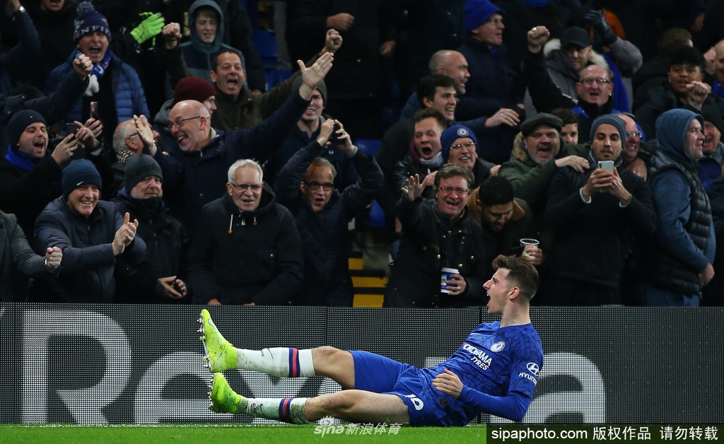 斯坦福桥球场外立面，巨大的“CHELSEA FC”字样下，一名戴着口罩的工作人员正在仔细张贴关于退票和慈善捐款说明的告示，透明的告示栏映出他专注的神情和身后空旷的广场。