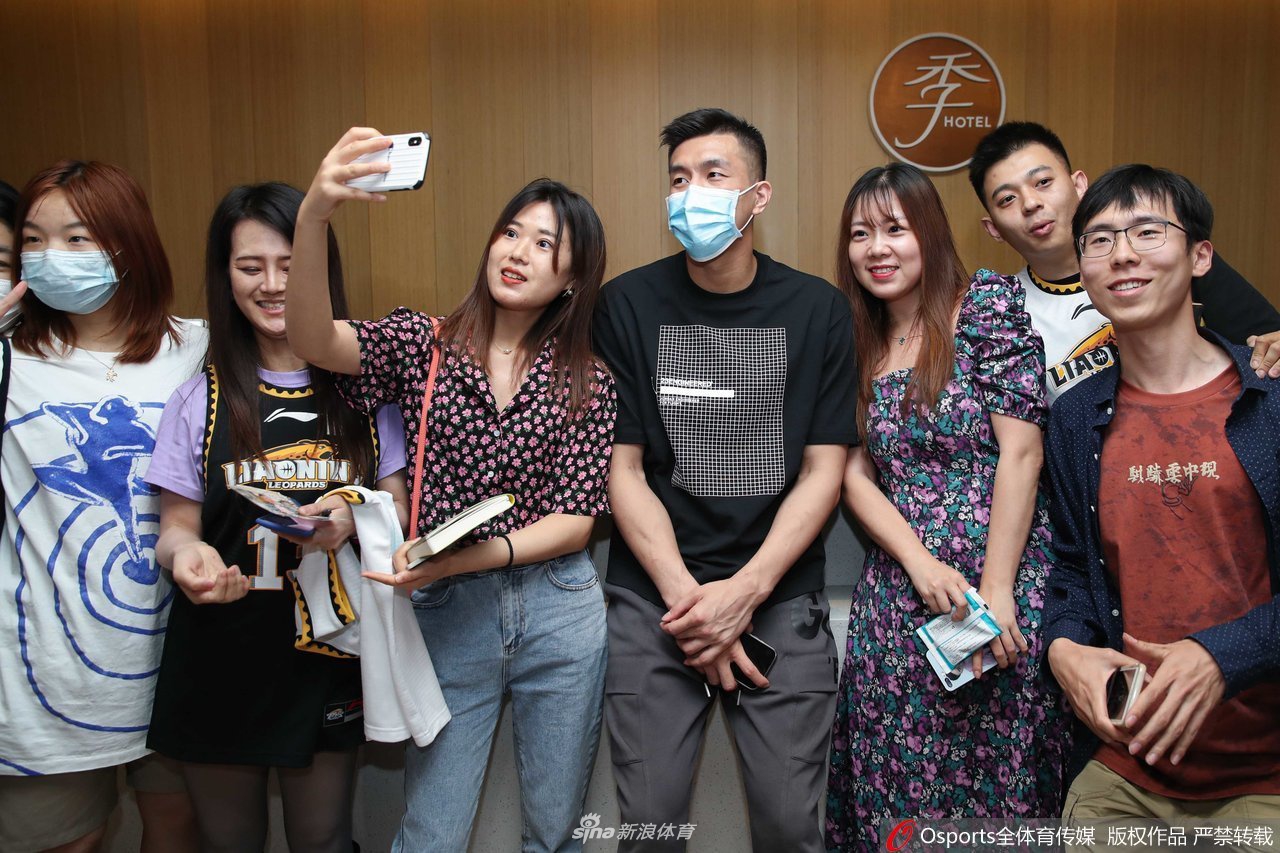 在人头攒动的酒店大堂门口，郭艾伦被热情的粉丝团团围住，他微微低头倾听粉丝的话语，现场气氛热烈而有序。