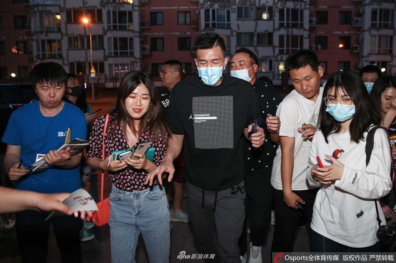 在粉丝的簇拥下，郭艾伦拉着行李箱缓步前行，他的侧脸轮廓分明，身边的女粉丝们依然紧追不舍地拍摄。