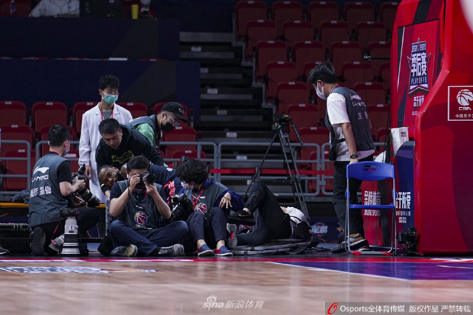 从另一个角度看，威姆斯身体已经失去重心，他与记者席的设备发生了剧烈碰撞，一台摄像机在重压下零件飞散，周围工作人员的脸上满是惊愕与担忧。