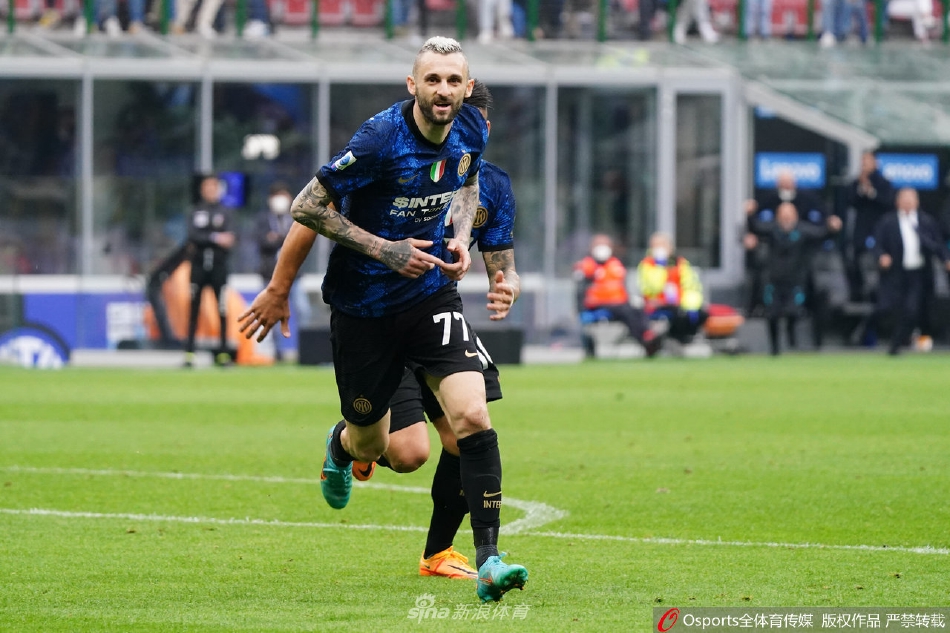 梅阿查球场全景，看台上蓝黑色旗帜迎风飘扬，场面宏伟壮观