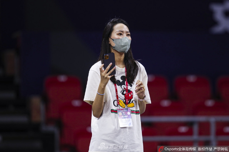 赛后喧嚣渐起，美女记者手拿记录本站在场边回眸，眼神清澈坚定，身后是正在退场的球员和忙碌的工作人员。