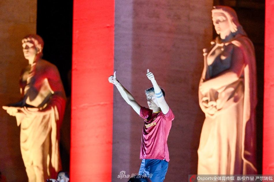 迪巴拉在万众欢呼中登上斗兽场前的舞台，瞬间被红黄两色的烟火与灯海笼罩