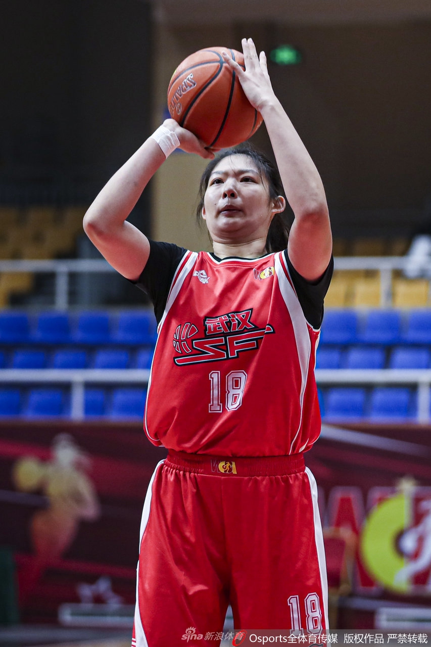 武汉队球员在三分线外果断出手，篮球在空中划出一道完美的弧线，她的眼神紧紧跟随篮球的轨迹，全场观众的目光都聚焦于此。