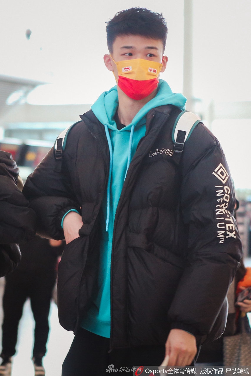 另一名浙江队球员在通过安检后回头张望,似乎在寻找同行的伙伴。背景中,候机大厅的灯光在地板上投下长长的倒影,整个画面充满了旅途开始前的动态与秩序感。