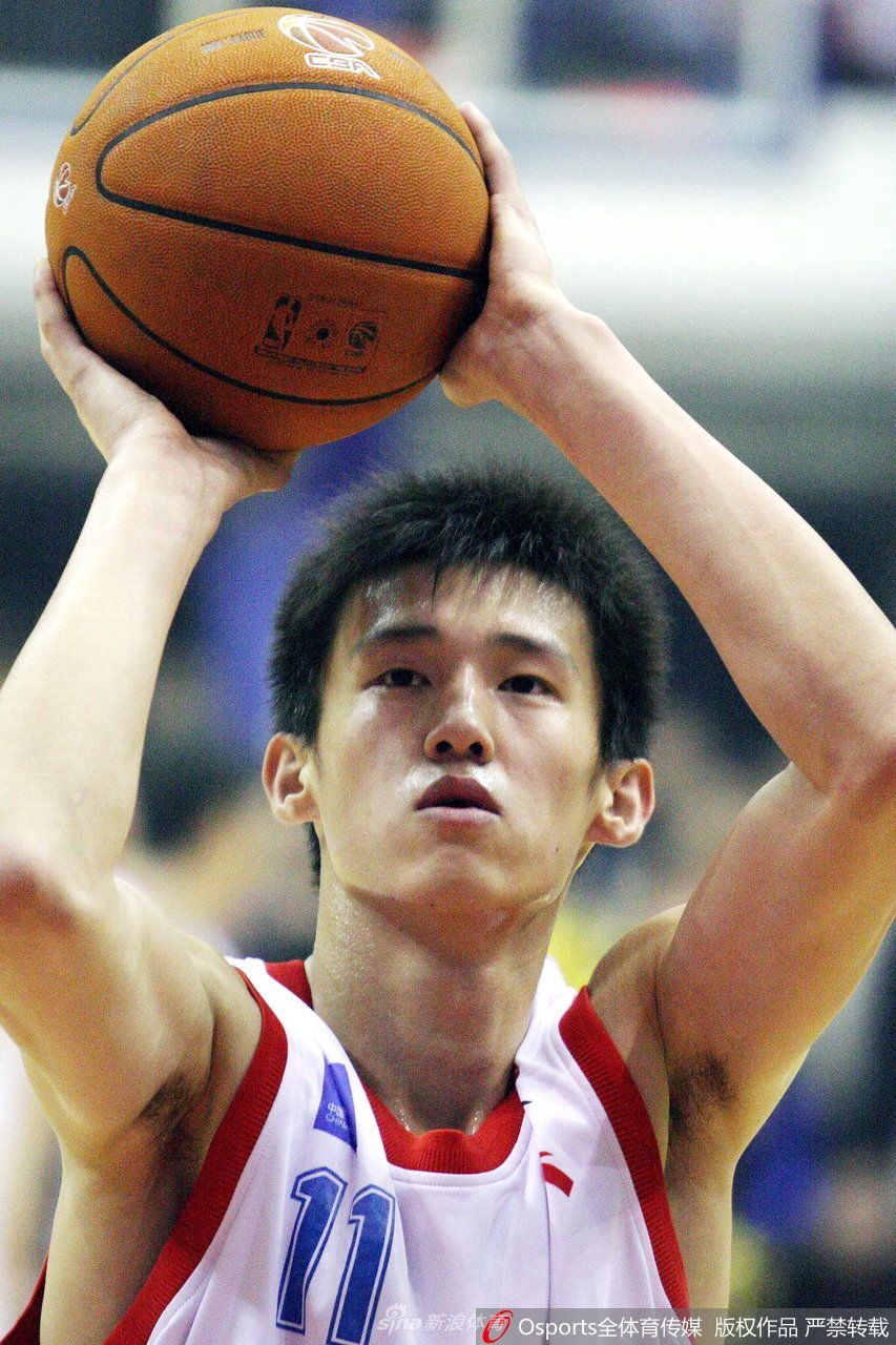 周鹏在国青队时期的老照片,他正专注地进行拉伸训练,额头的汗珠清晰可见,背后是熟悉的橘红色篮球