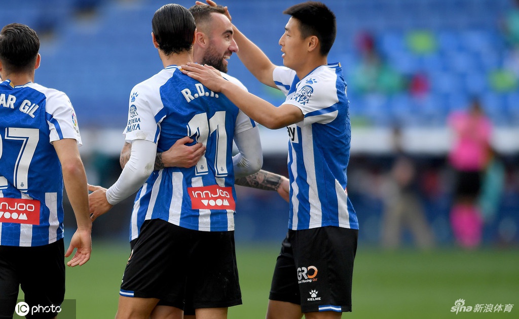 武磊在赛前热身时神情轻松，正在进行拉伸训练，他身后的看台上悬挂着巨大的西班牙人队徽，一切准备就绪只待比赛开始。