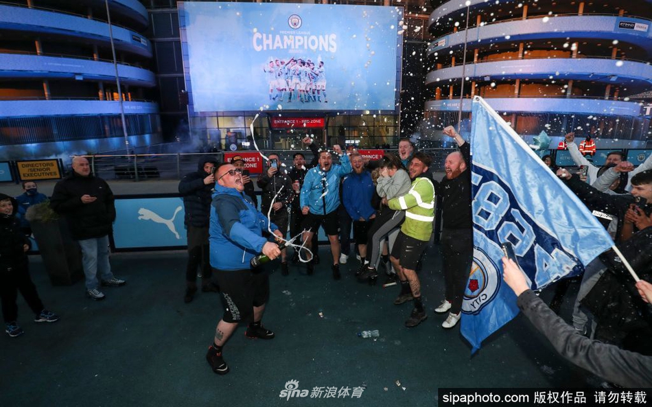 夜幕低垂，伊蒂哈德球场被蓝色的烟雾照亮，数不清的曼城球迷在看台外的广场上振臂高呼，蓝色的旗帜在风中猎猎作响，仿佛一片由激情汇聚成的蓝色海洋。
