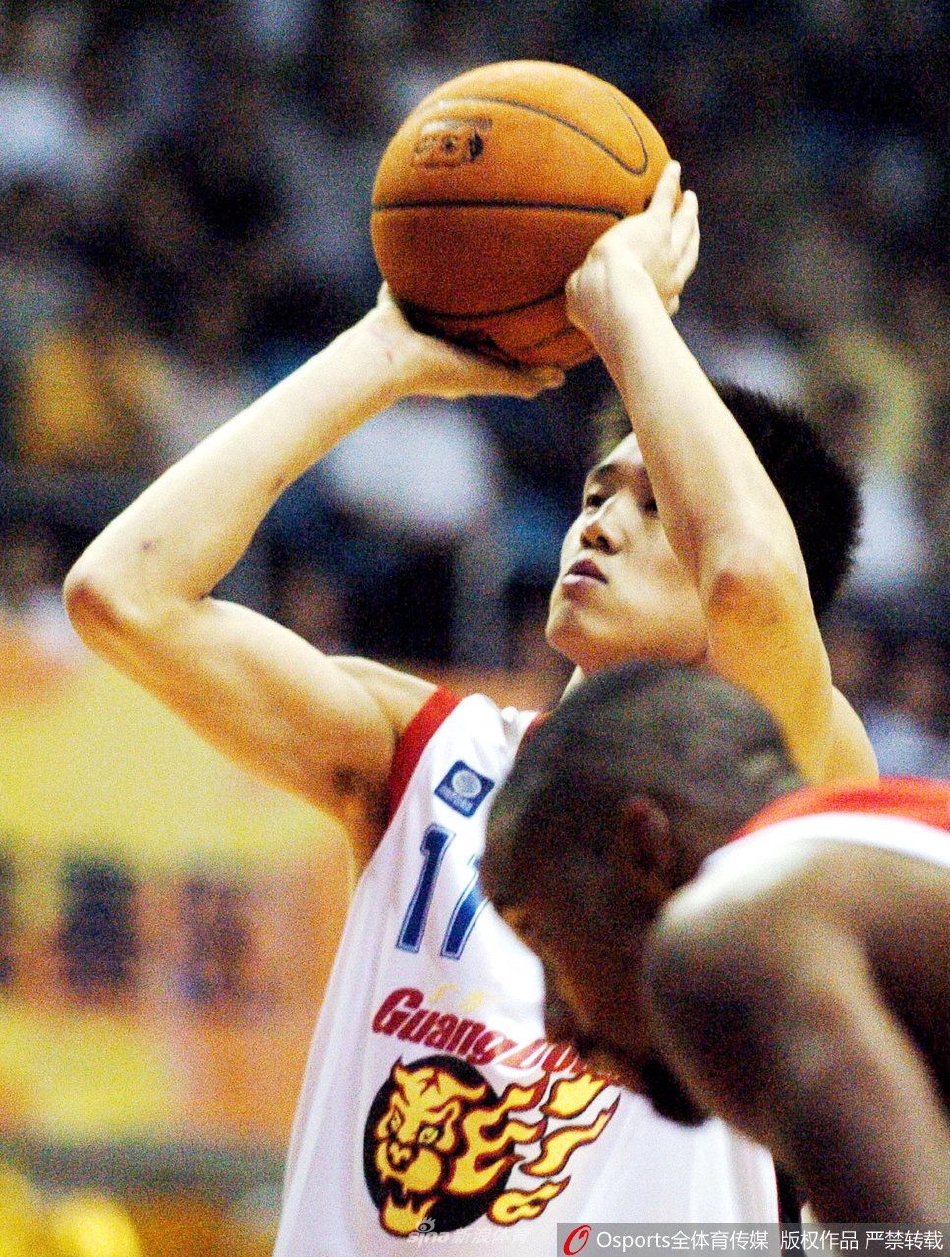 训练间隙的周鹏坐在地板上擦汗,眼神望向远方若有所思,背景是空旷的体育馆,阳光透过高窗洒下