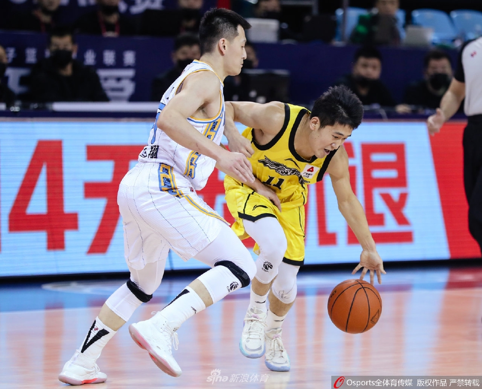 吉林队核心外援琼斯持球强行突破，他遭遇了北京首钢队翟晓川与范子铭的严密包夹。尽管寸步难行，琼斯依然奋力护球，眼神中透露着不甘与坚韧。