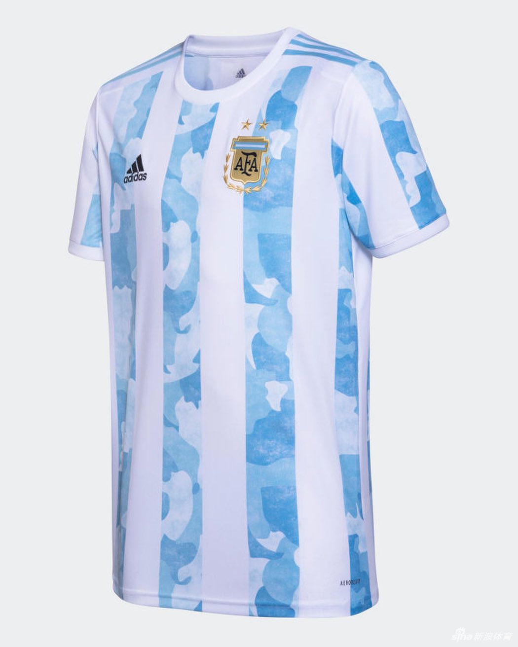 梅西低头沉思，目光温柔地落在胸前的阿根廷足协徽章上。背景的虚化处理让焦点完全集中在球衣精致的迷彩纹理与他深邃的神情之间，营造出一种静谧而有力的故事感。