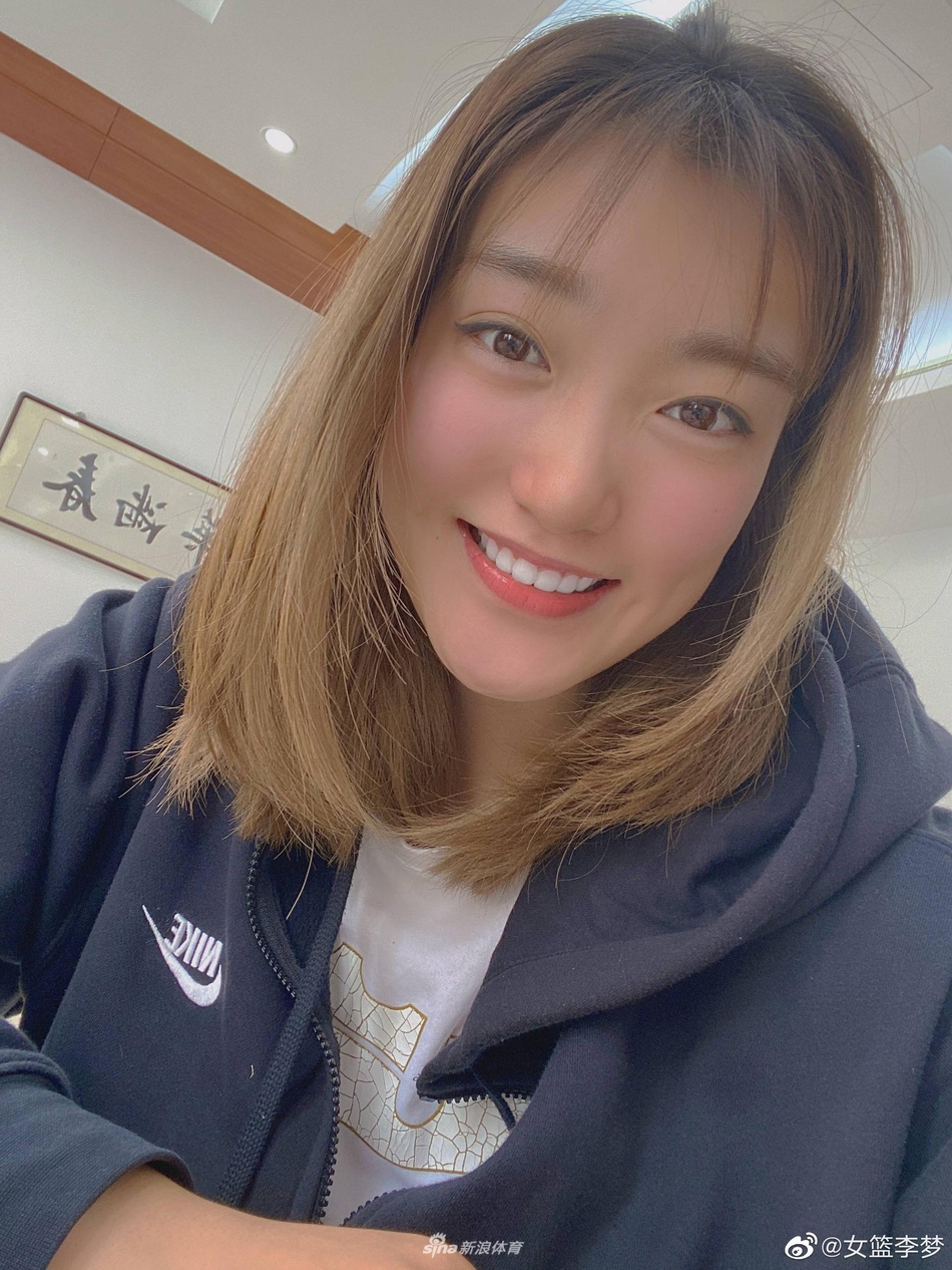 李梦身穿休闲装倚靠在墙边，微微侧身，展现出训练场下安静温柔的一面，气质出众。