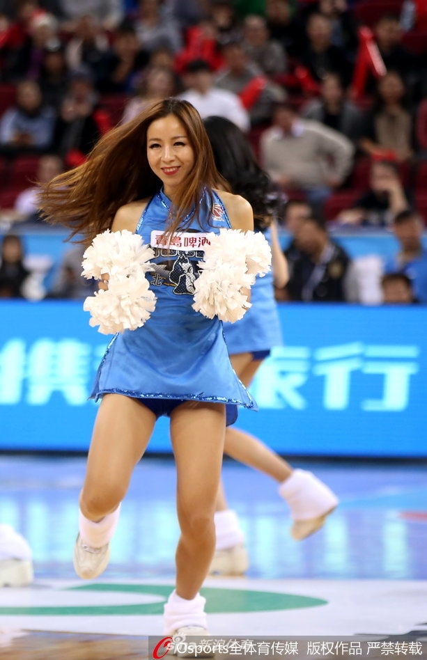 一位队员在聚光灯下回眸，眼神中闪烁着坚定与温柔，背景是虚化的赛场看台，这张照片定格了啦啦宝贝赛场之外的动人瞬间。