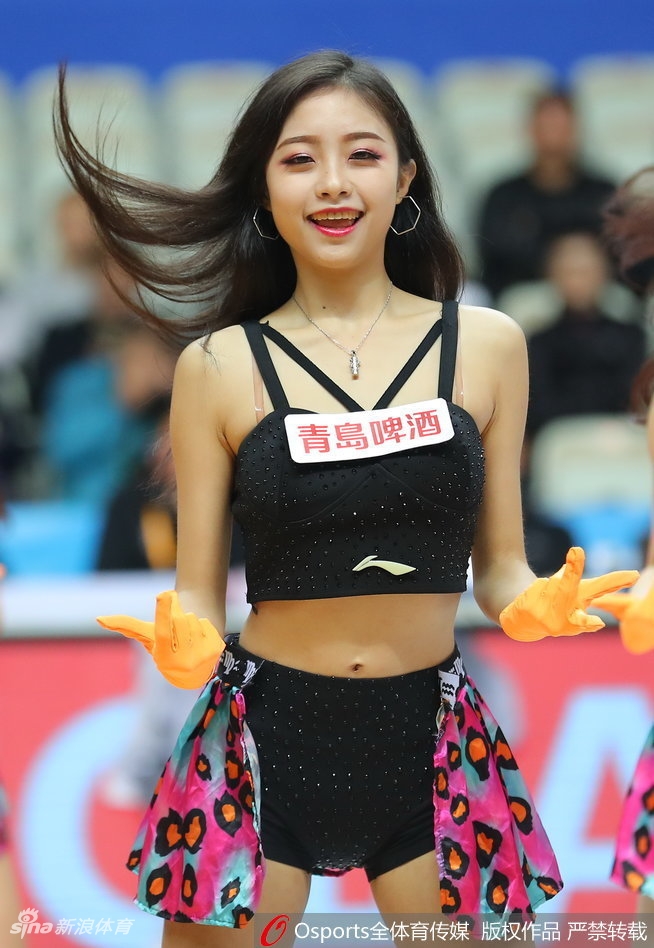 在柔和的光影下，一名拉拉队员单手叉腰侧身站立，紧身的表演服勾勒出优美的身材曲线。她面容精致，嘴角含着一抹浅浅的微笑，甜美中带着一丝羞涩，宛如从画中走出的邻家女孩，让人移不开眼。