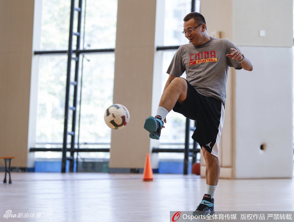 范斌俯身亲自示范标准的防守滑步动作，每一个细节都力求完美，展现出作为专业教练的严谨与扎实的基本功。