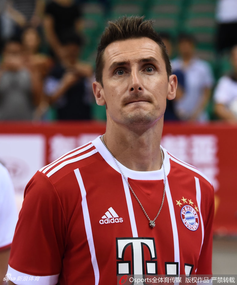 克洛泽与中国男篮队员在场边互动交流，他高大的身影在篮球运动员身边也不显矮小，手势比划着仿佛在讨论刚才的某个精彩进球。