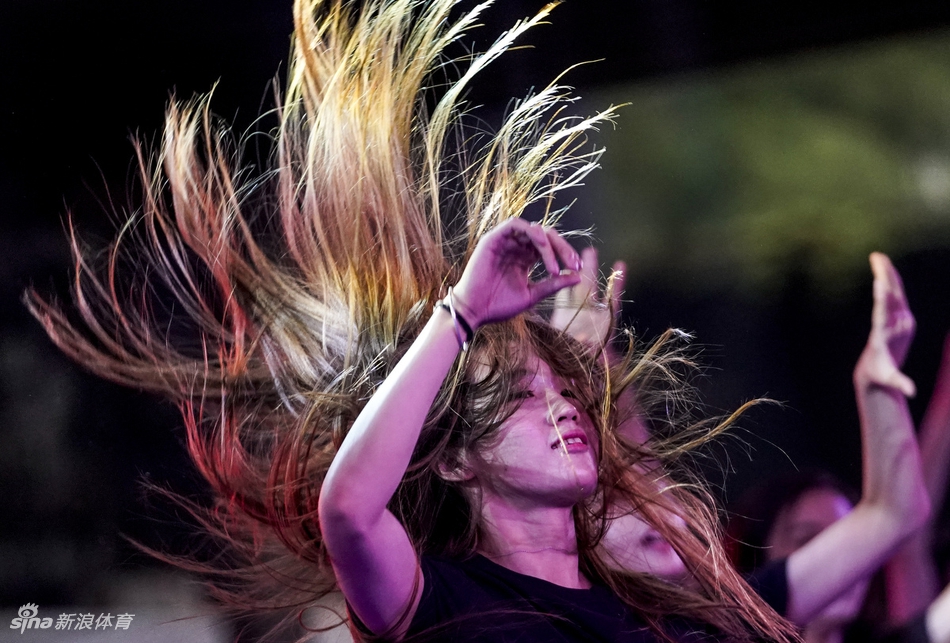 活动现场的Hip-hop舞者正在进行暖场表演，他们动作整齐划一，充满青春的律动，背景是色彩鲜明的联赛标志，将街头文化与竞技体育完美融合。