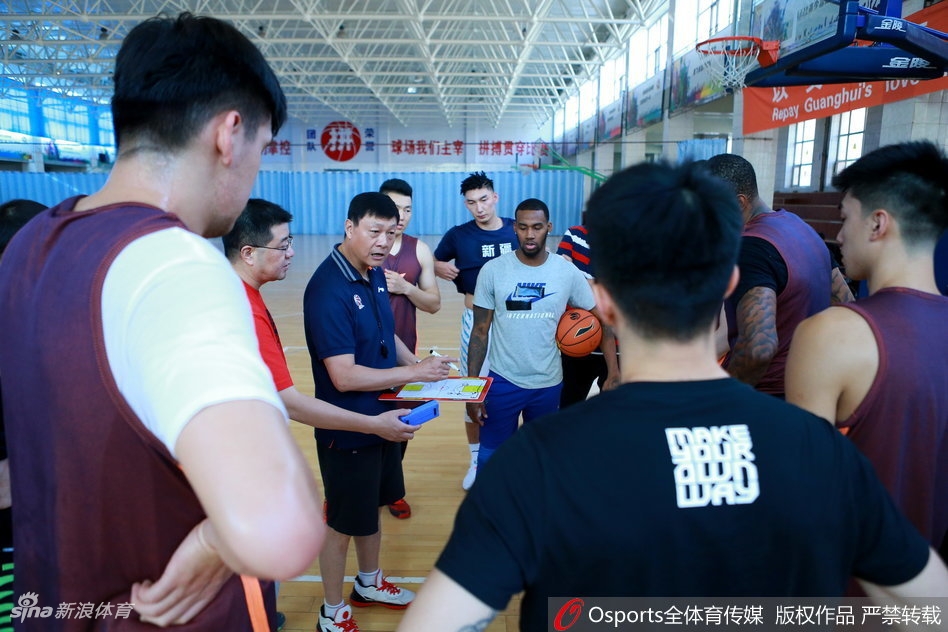 飞虎训练营内，主帅李秋平神情专注，双手比划着复杂的战术跑位，队员们围成一圈，眼神中透露出对胜利的渴望。