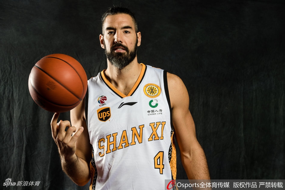 一名山西男篮年轻队员正在进行个人动作写真拍摄，他高高跃起试图完成单手劈扣，身体在空中充分伸展，充满了力量感与爆炸性的视觉冲击。