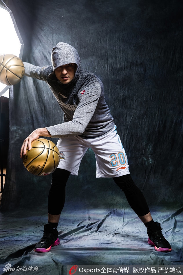 西热力江目光如炬凝视前方,身着时尚嘻哈卫衣,背景是暗色调的都市街头,仿佛在静候对手的挑战