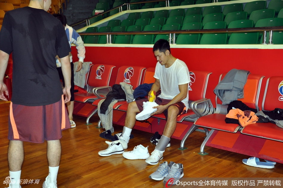 主教练邱彪在训练间隙为球员耐心讲解战术，手势坚定，神情严肃，队员们围成一圈认真聆听，团队凝聚力十足。