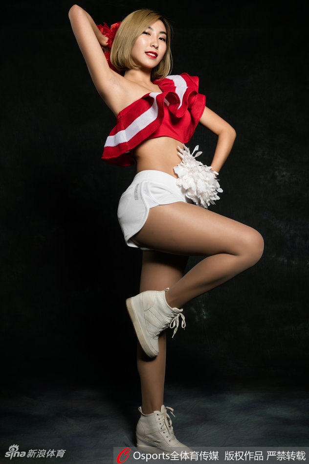 写真镜头下，篮球宝贝轻抚秀发，红装似火，妩媚姿态与背景光影交织，定格了赛场外的柔美瞬间。