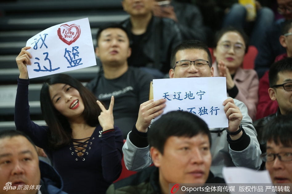 三位辽宁美女球迷在场边合影留念，笑容灿烂，她们身穿统一的辽篮助威服，青春洋溢，用笑容为球队加油打气。