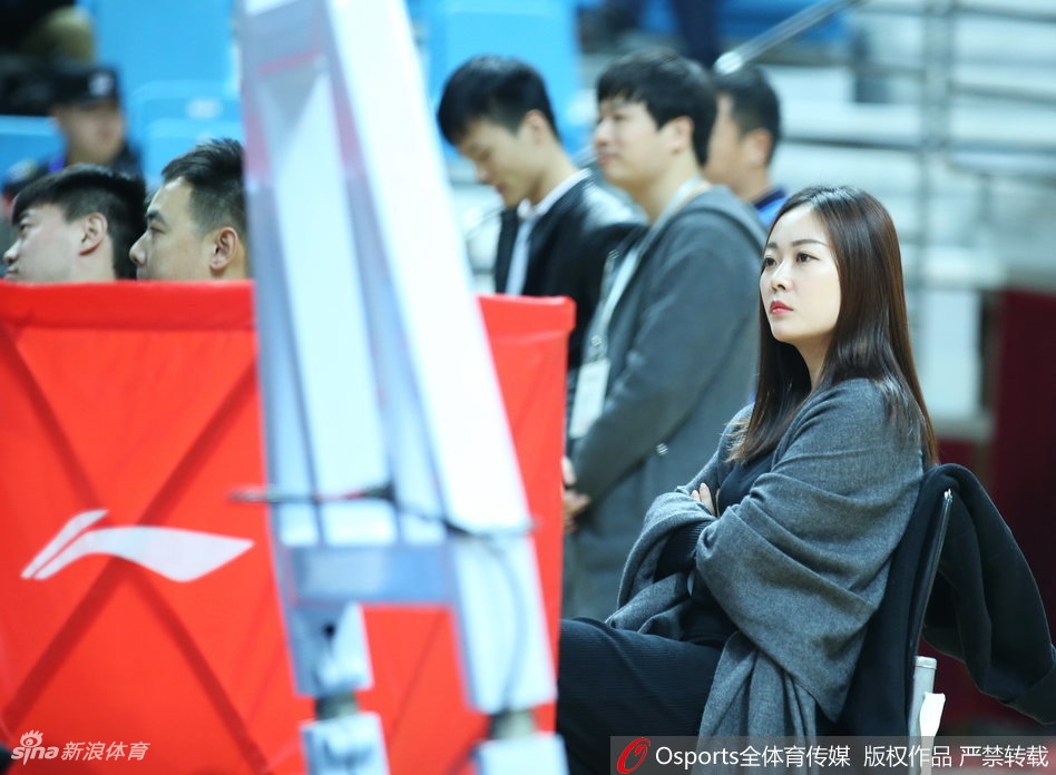 在青岛主场明亮的灯光下,一位戴着眼镜的女球迷回眸瞬间,眼神中透着对比赛的专注与好奇,文艺气息十足