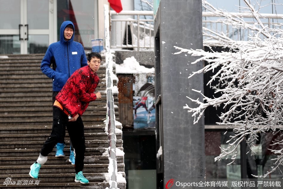 广厦球员在乌鲁木齐雪地中漫步,一行人在雪地上留下深浅不一的脚印,背景是冬日里静谧的城市景色。