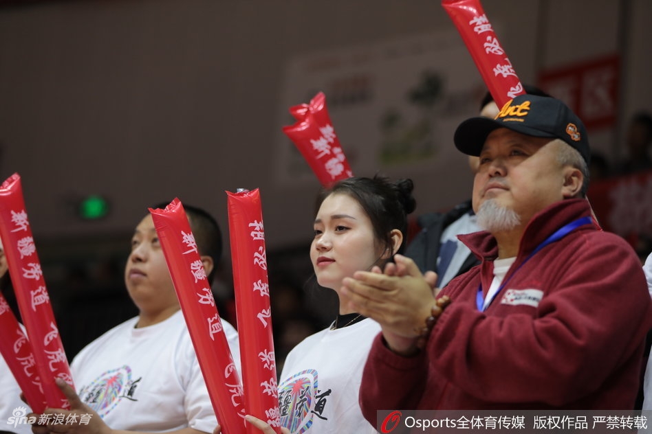 一位颜值出众的新疆美女球迷,目光专注地望向赛场方向,眼神中充满了对比赛的期待。