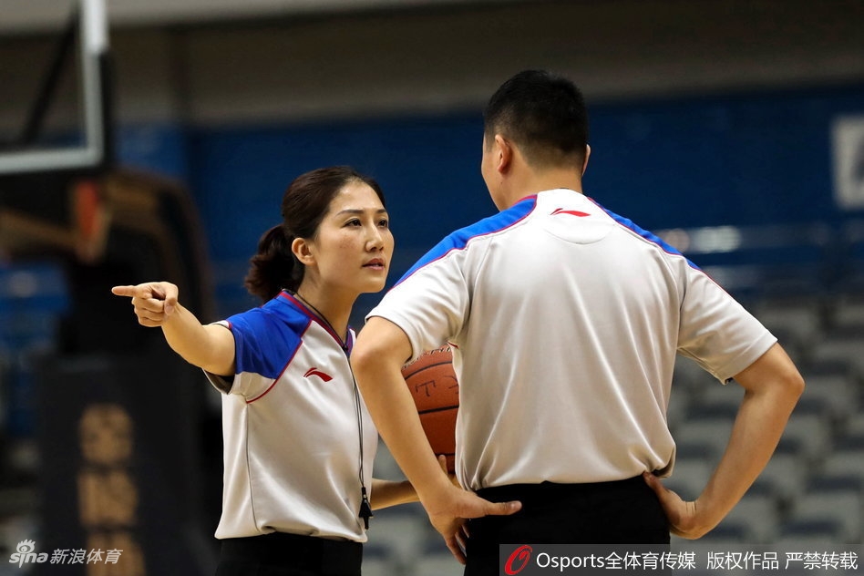 女裁判在人群中高高跃起，与争抢篮板的球员们一同腾空，她张开手臂维持着争球秩序