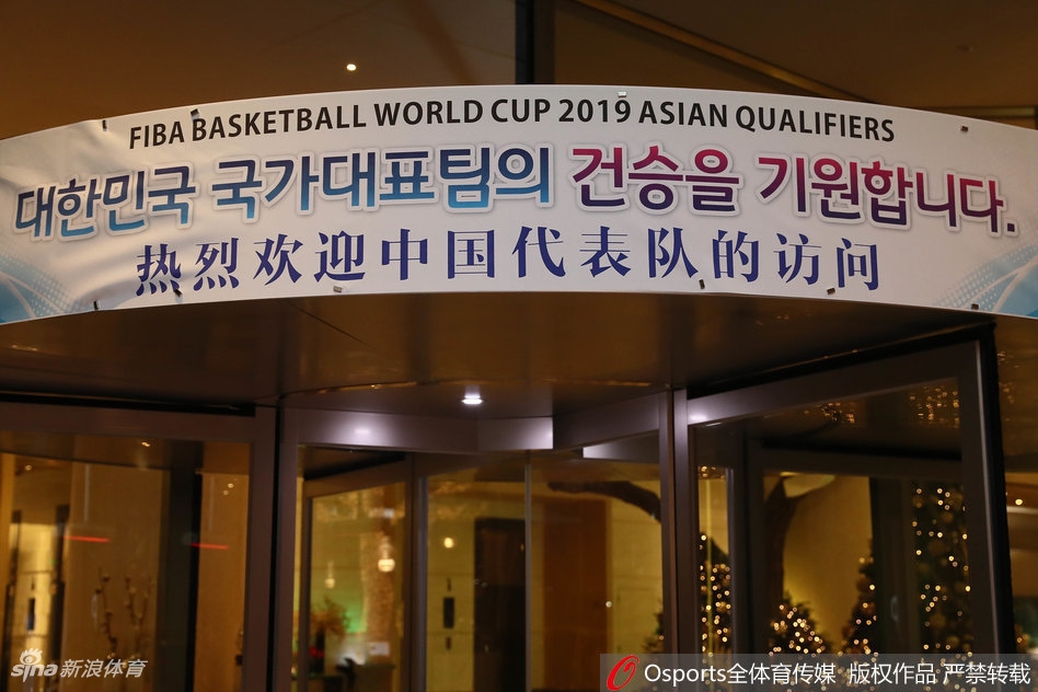 球员通道内，王哲林穿着便装与队友说笑，轻松的表情感染着周围人，身后墙上巨大的世预赛海报预示着这里即将成为热血战场。