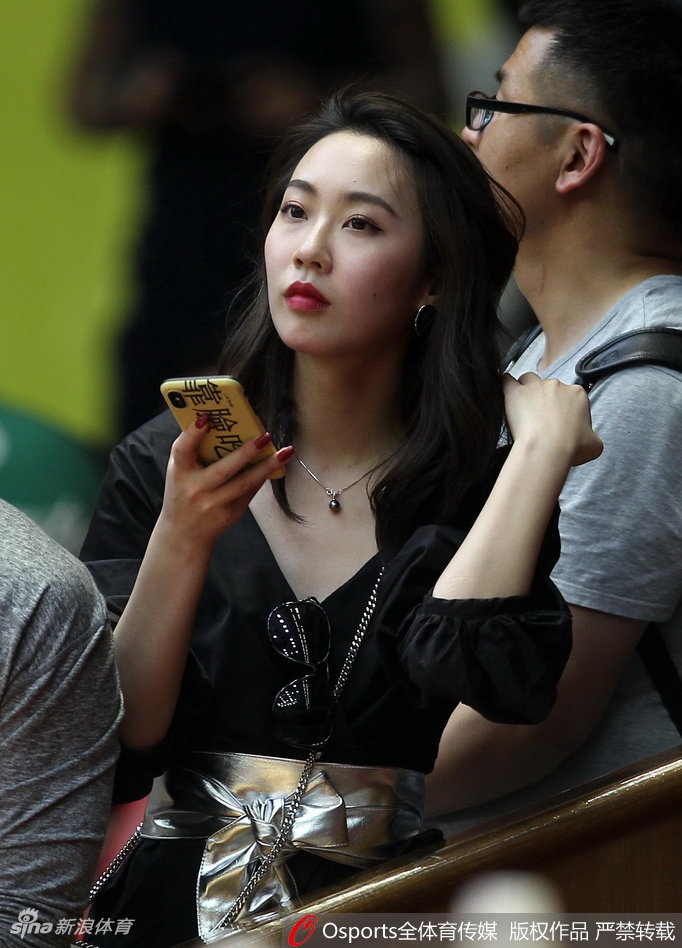 一位长发披肩的广厦女球迷回眸一笑，眉眼间满是对主队晋级的期盼，手中挥舞的助威棒与脸上的油彩交相辉映。