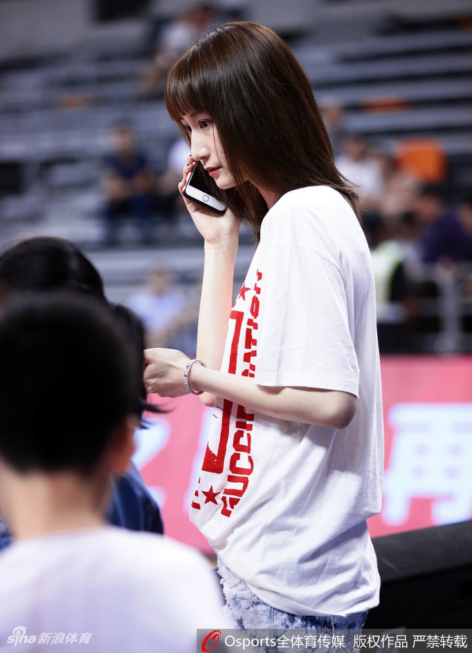 刘美微微侧身，大长腿在座位间格外引人注目，她面带恬静微笑，仿佛赛场的喧嚣与她无关，她的世界里只剩下为那个男人的每一次奔跑而跳动的心。