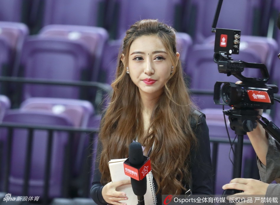 总决赛G4赛前，辽宁主场的美女主持人身着一袭优雅长裙，手持话筒，脸上洋溢着自信而温柔的笑容，静静伫立在球场中央，等待着大战的启幕。