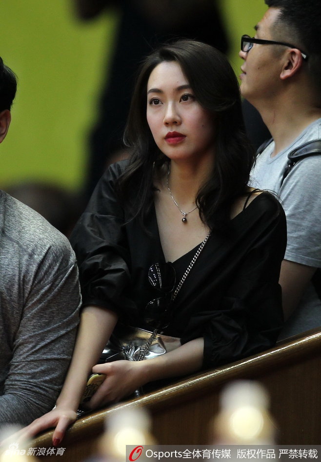 一位戴着黑框眼镜的广厦美女球迷双手比出爱心手势，专注地看着场内，她的眼神中透露着对广厦男篮深深的眷恋和支持。