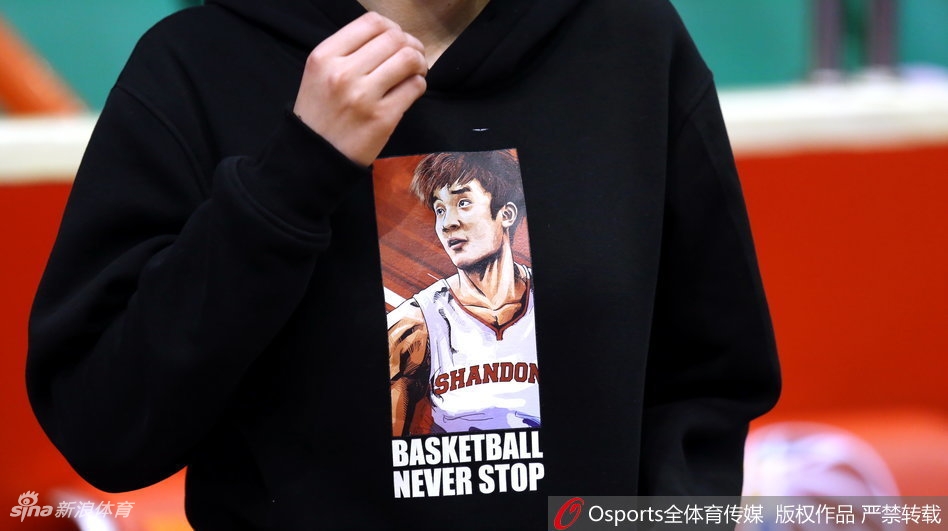 一位身穿印有丁彦雨航名字和数字的球迷，双手扶着栏杆，在比赛暂停间隙眺望球场中央，背影显得既期待又有些许紧张