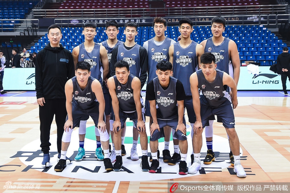 全景镜头下，整个训练馆一览无余。多个半场同时进行着不同的训练项目，有投篮练习、有战术跑位、还有体能训练。色彩鲜艳的球衣点缀着灰色的地板，像一幅充满动感的现代油画。